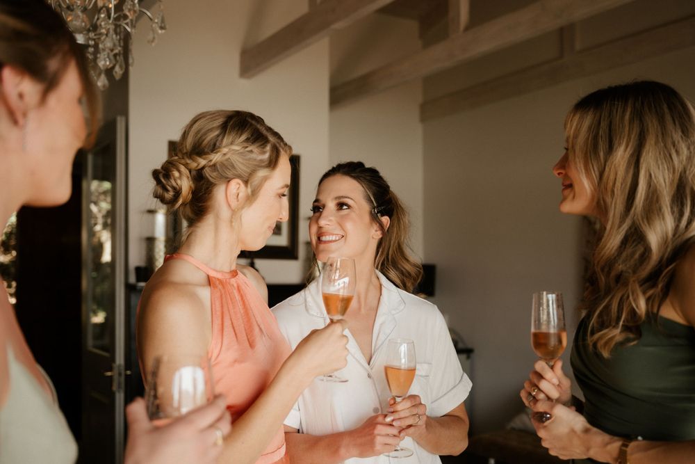Wedding guests sharing champagne and laughter during pre-ceremony preparations.