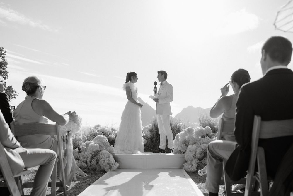 Black and white photo of wedding ceremony with mountains in background.