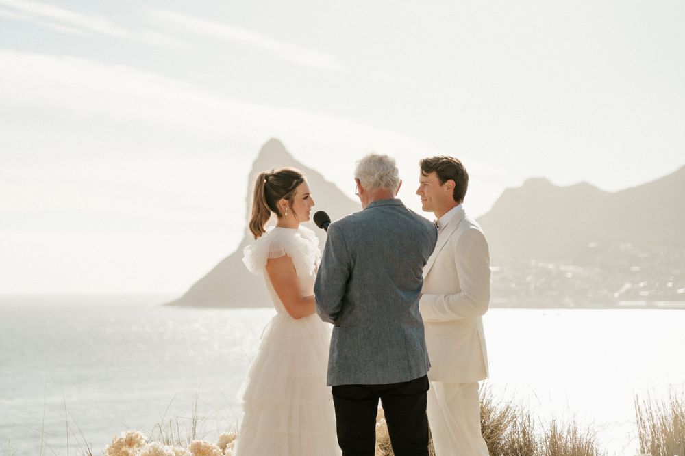 Outdoor wedding ceremony taking place on scenic coastal overlook.