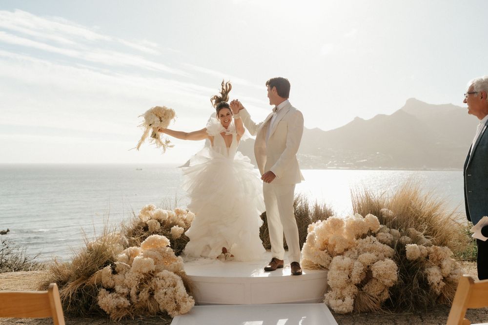 Wedding ceremony setup with pampas grass decorations overlooking coastal mountain scenery.