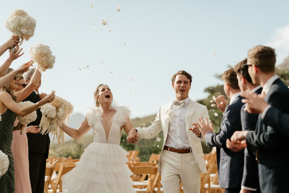 Wedding celebration with guests tossing flowers during outdoor ceremony.