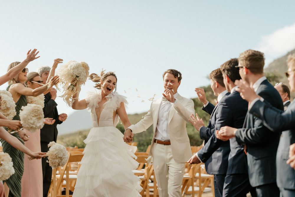 Joyful celebration moment at outdoor mountain wedding with guests throwing confetti.