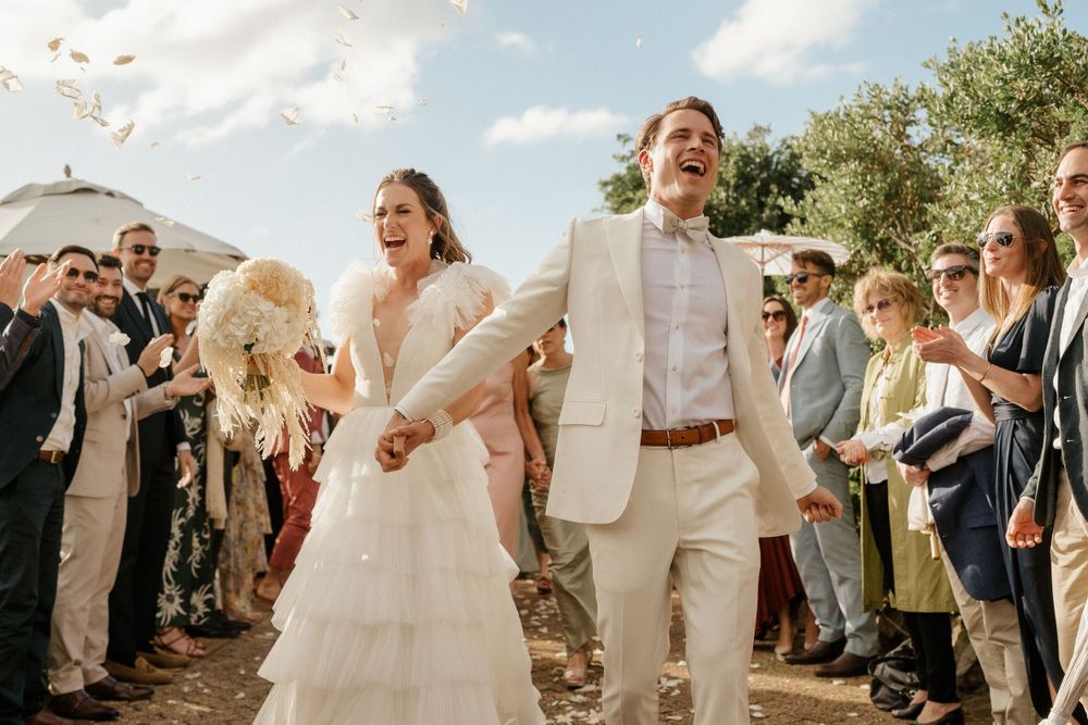 Newlyweds celebrating during wedding recessional with guests throwing confetti.