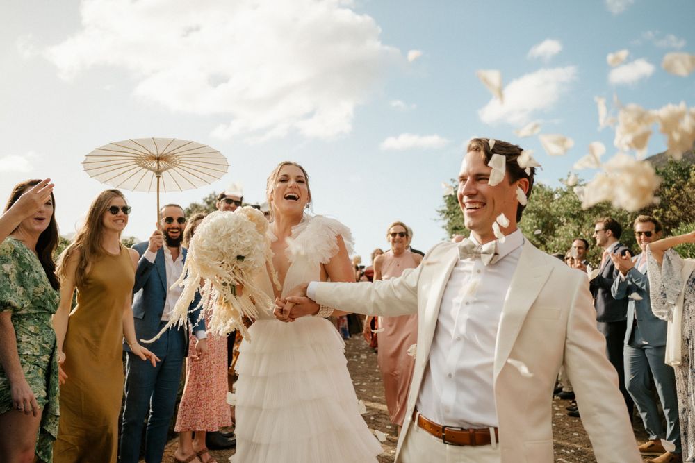 Joyful celebration with parasol and guests during an outdoor wedding reception.