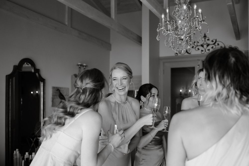 Wedding guests raise champagne glasses under elegant crystal chandeliers during reception celebration.