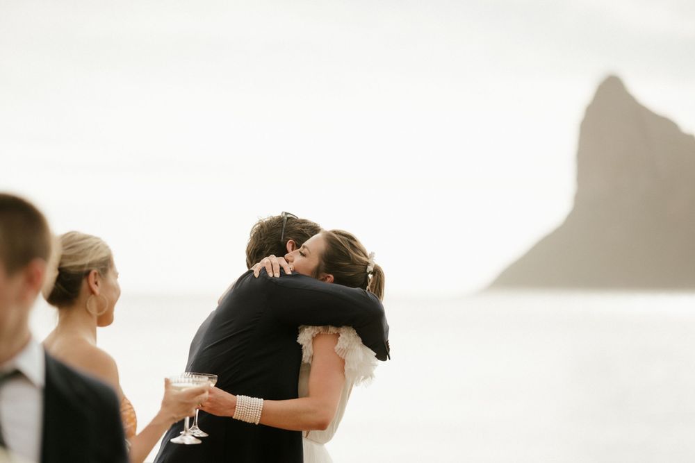 Intimate moment between wedding attendees with mountain silhouette in background.