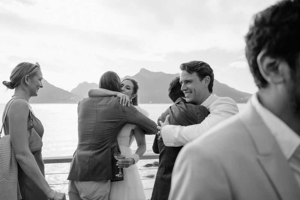 Wedding guests sharing joyful moments at an oceanside celebration.