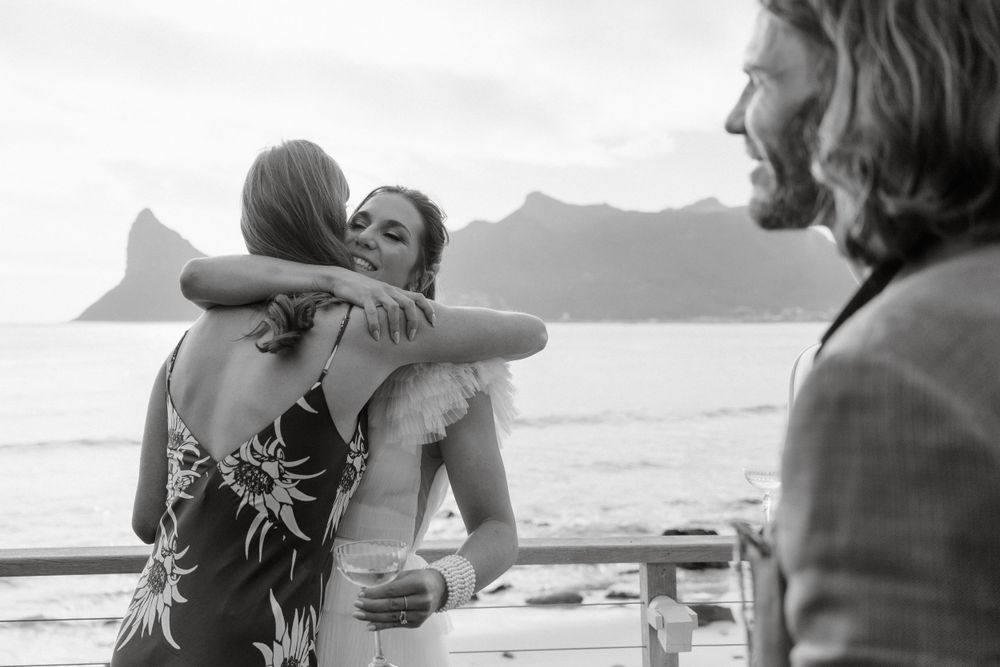 An intimate seaside gathering with mountain views in the background during a celebration.