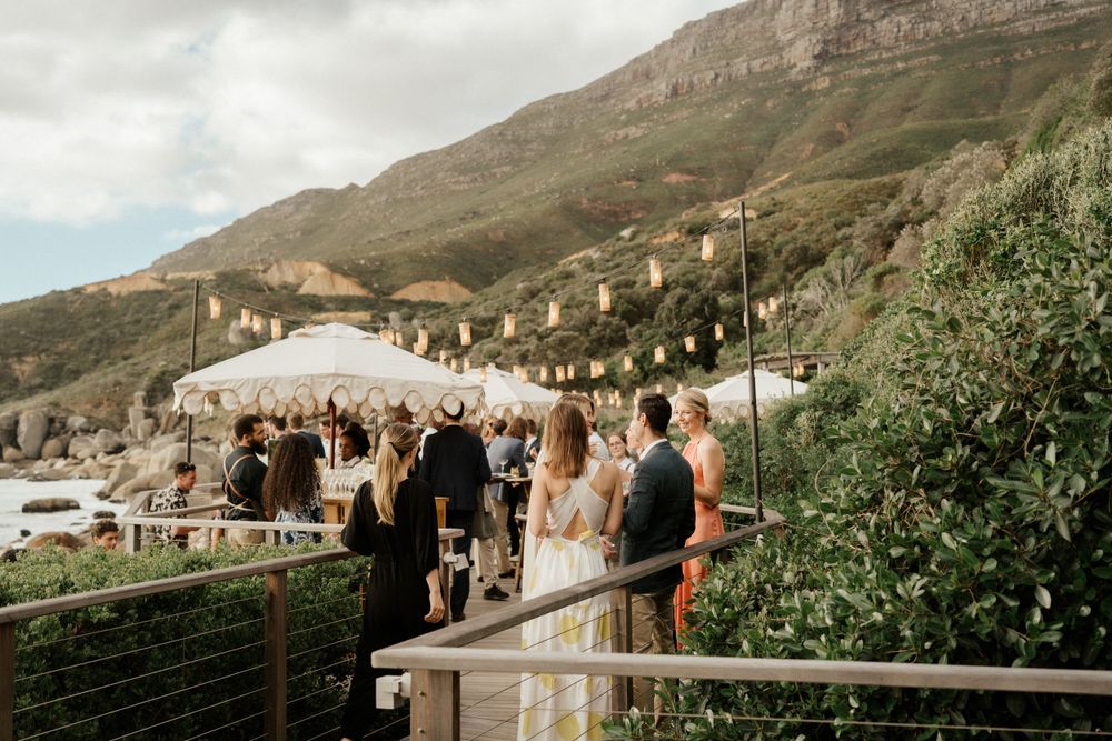 Outdoor wedding venue with white tent and mountain backdrop during daytime celebration.