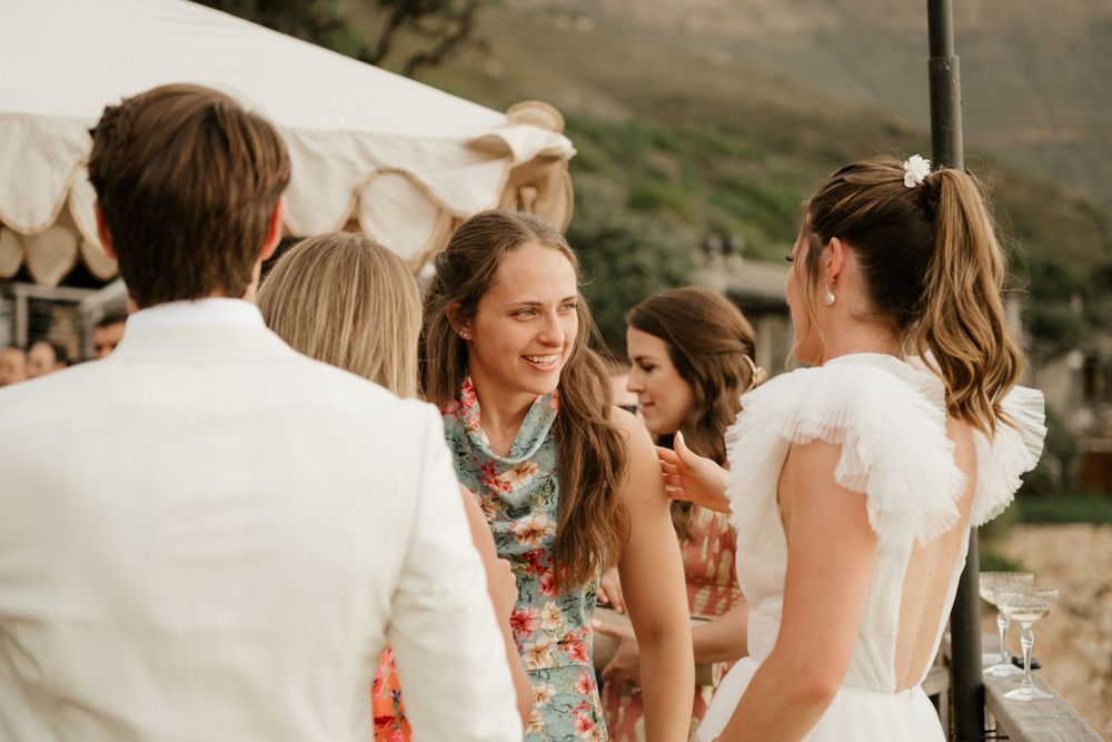 Wedding guests in summer attire chatting during an outdoor celebration.