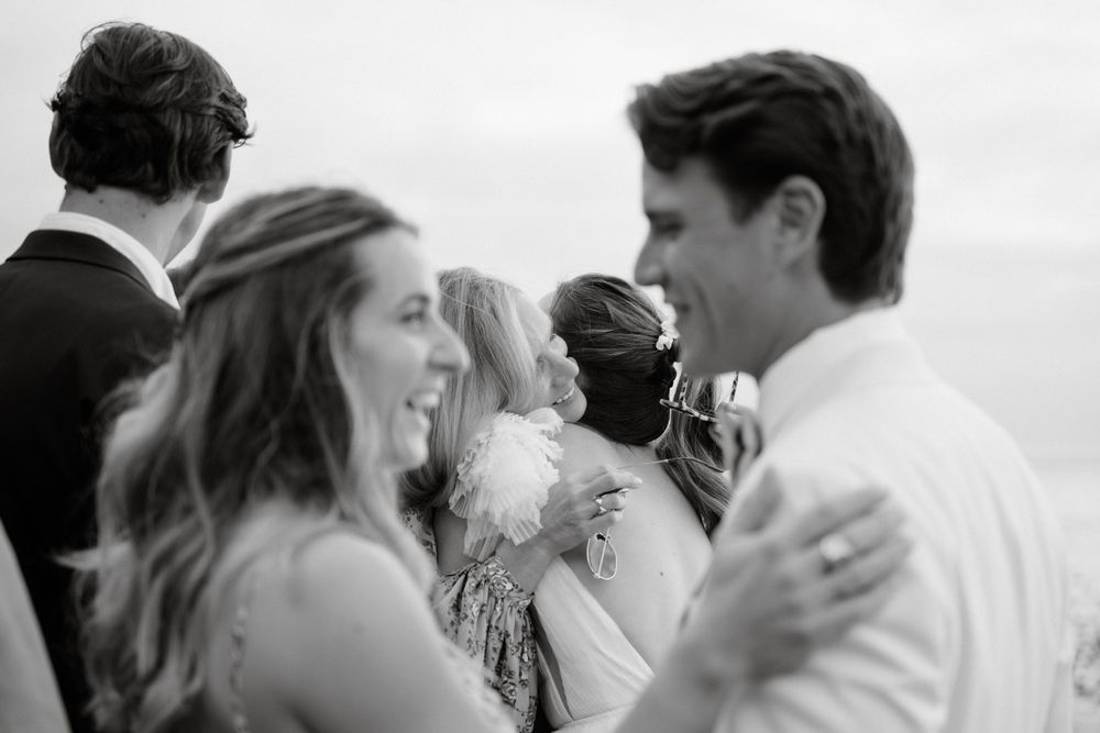 Black and white candid moment of wedding guests celebrating at outdoor reception.