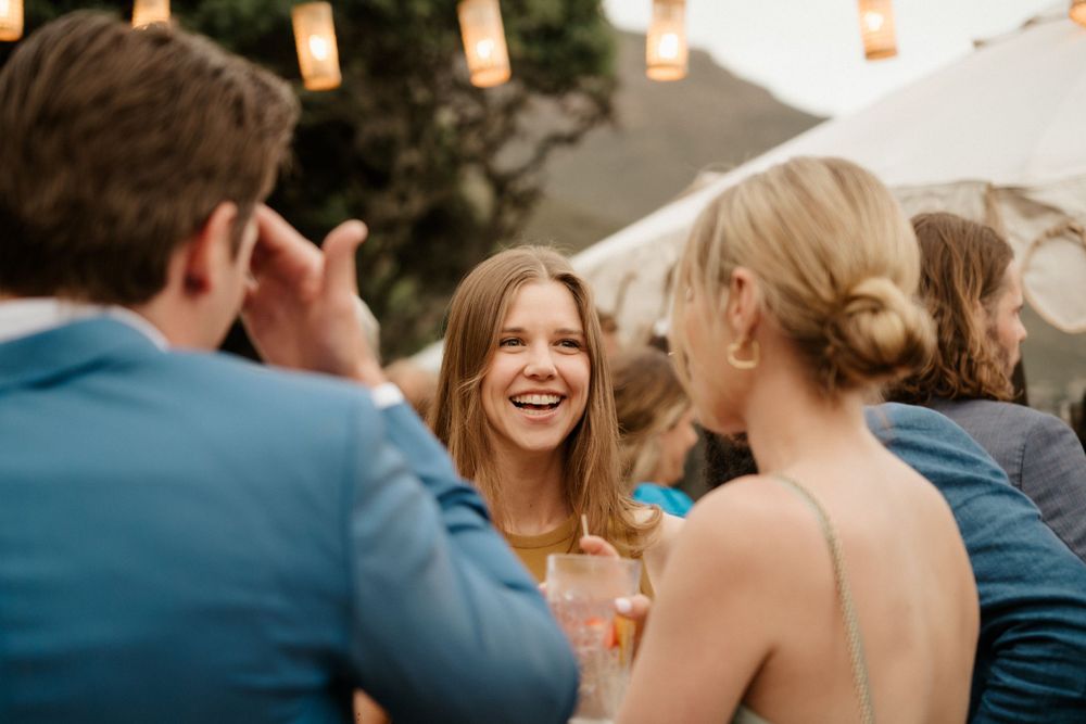 Wedding guests share laughter during evening reception with warm lighting.