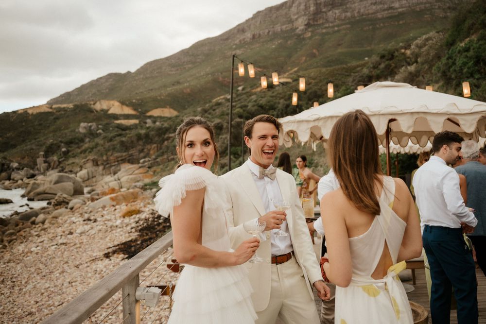 Coastal wedding celebration with string lights and mountain views.