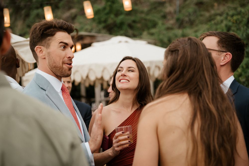Guests enjoying conversation at an elegant outdoor wedding reception under glowing lanterns at dusk.