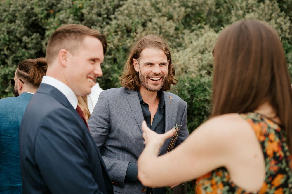 Guests engage in animated conversation at an outdoor wedding reception.
