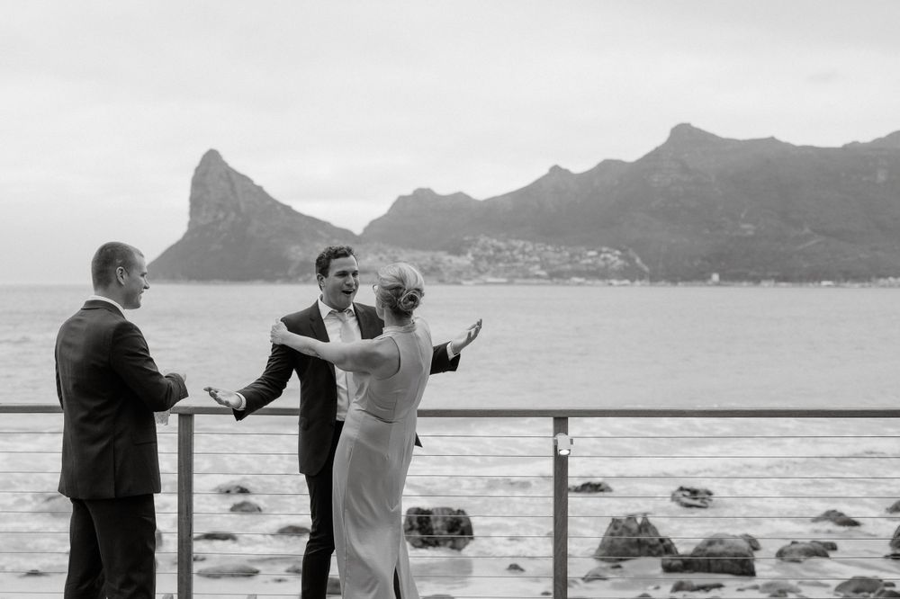 Black and white photo of wedding moments on coastal deck with mountain backdrop.