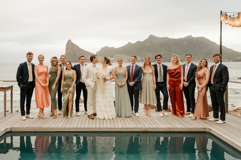 Formal group photo of wedding party on pool deck with dramatic mountain vista.