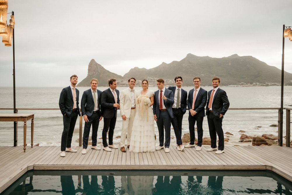 Formal wedding party portrait on a deck overlooking mountains and water.