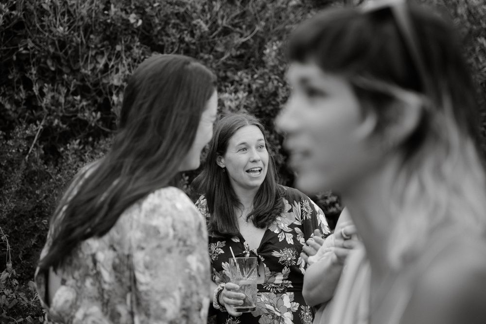 Black and white candid shot of friends laughing together at an outdoor gathering.