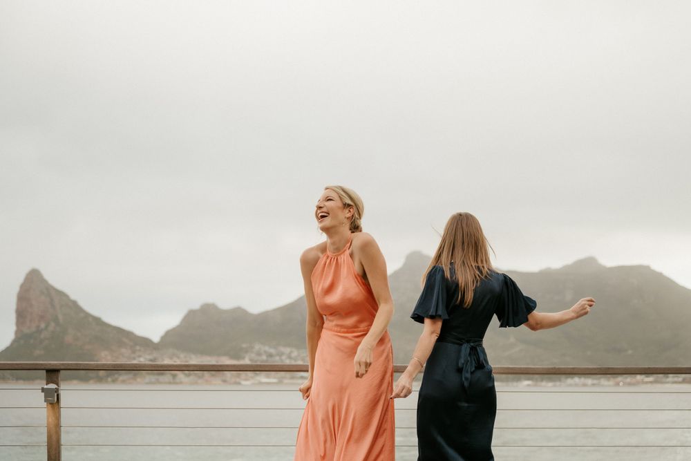 Two guests in formal attire dance on deck with scenic mountain view.