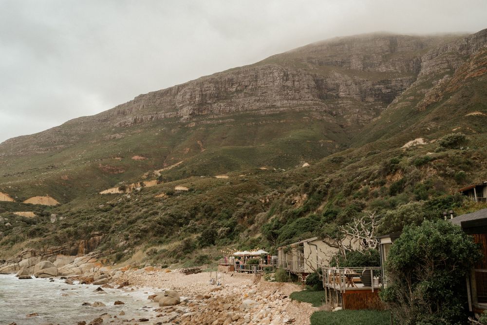 Rugged coastal landscape with mountains and beach houses along the shoreline.