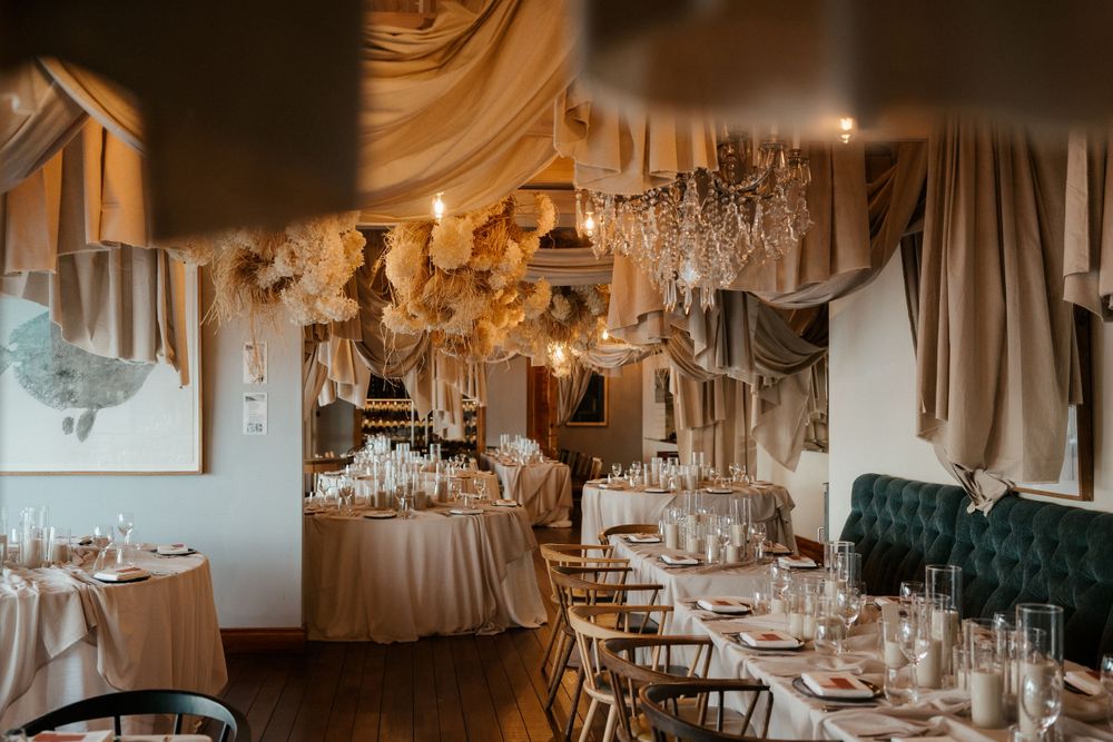 Elegant wedding reception room with crystal chandeliers and draped fabric decorations.