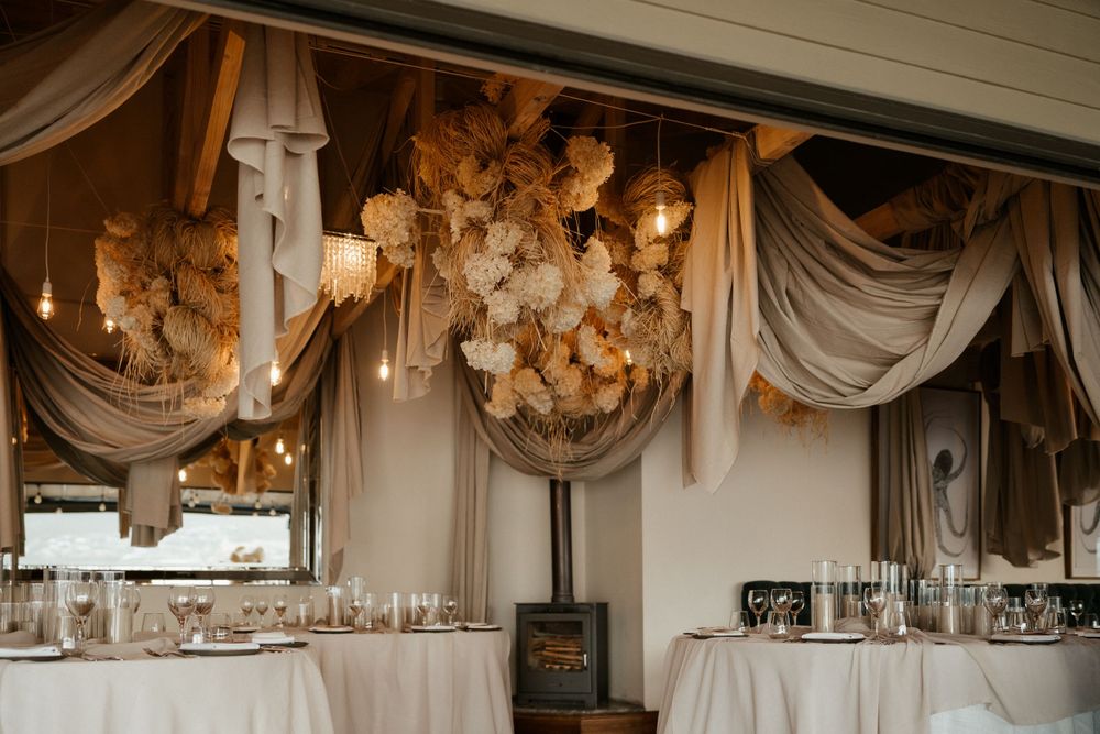 Elegant wedding reception decor with draped fabrics and hanging floral installations.