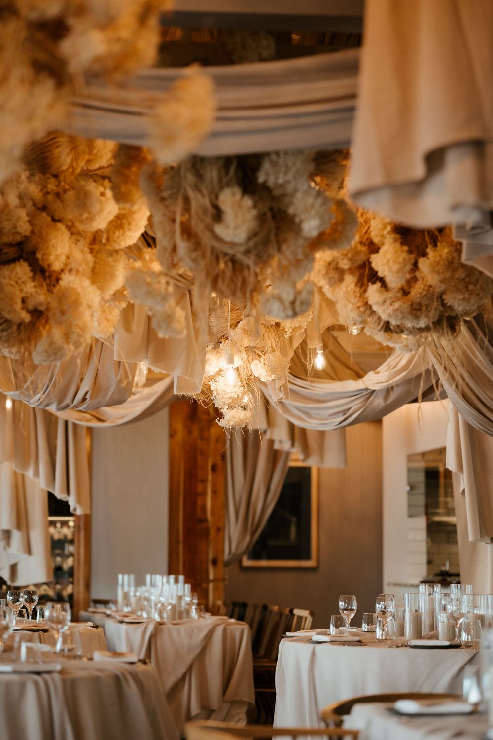 Elegant wedding reception venue with dramatic draped fabric and floral ceiling installations.