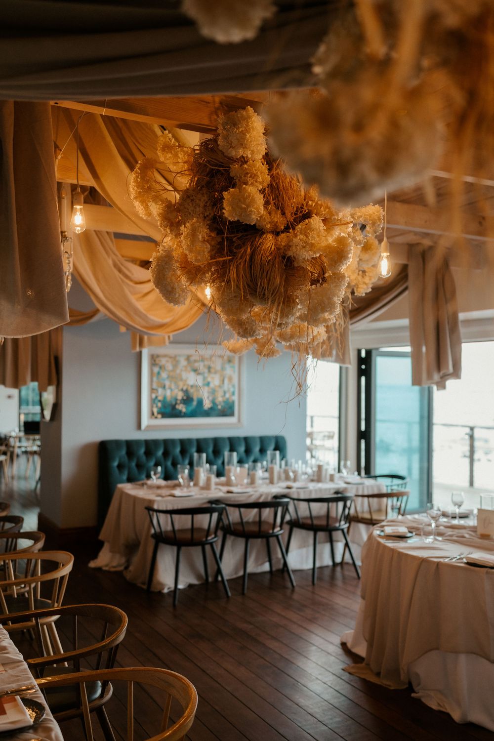 Rustic wedding reception space with flowing fabric drapes and cloud-like ceiling installations.