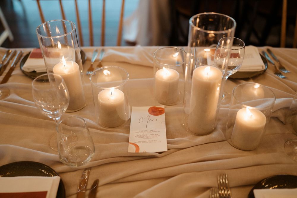 Romantic table setting with glowing white candles and wine glasses creating an intimate atmosphere.