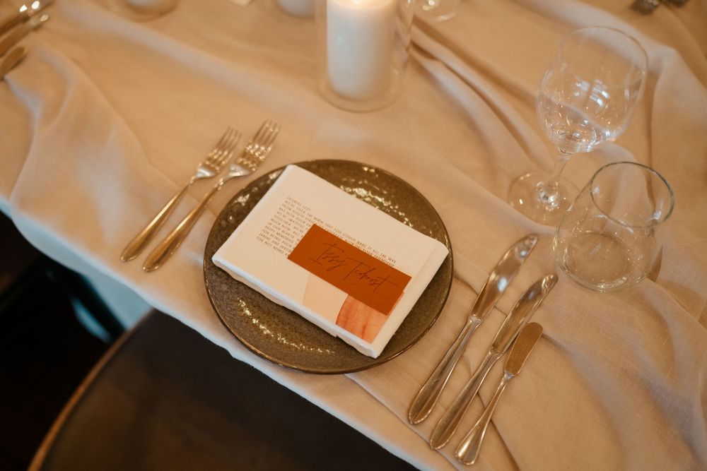 Formal place setting at wedding reception with white tablecloth and menu card.