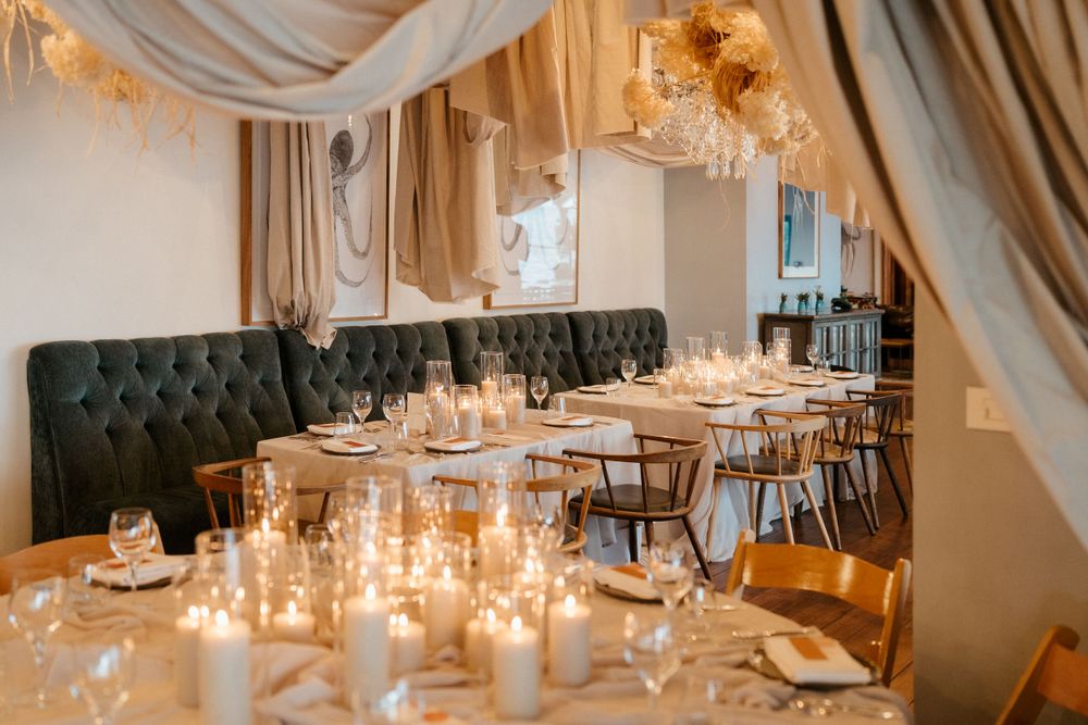 Elegant restaurant dining room with tufted banquette seating and soft candlelight illuminating tables set for dinner service.