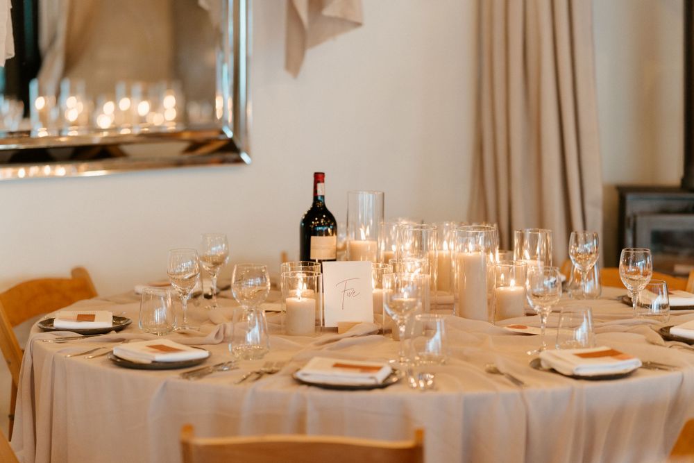 Elegant wedding reception table set with candles, wine glasses and place settings.