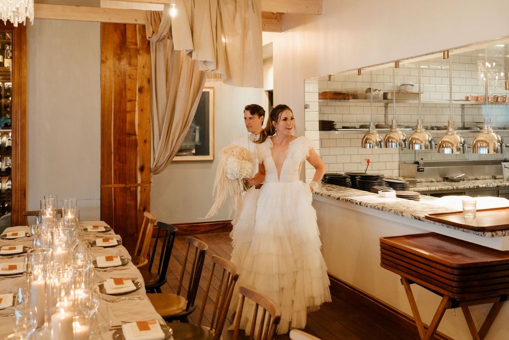 Elegant dining room setup with candlelit tables and white draping for an intimate wedding reception.