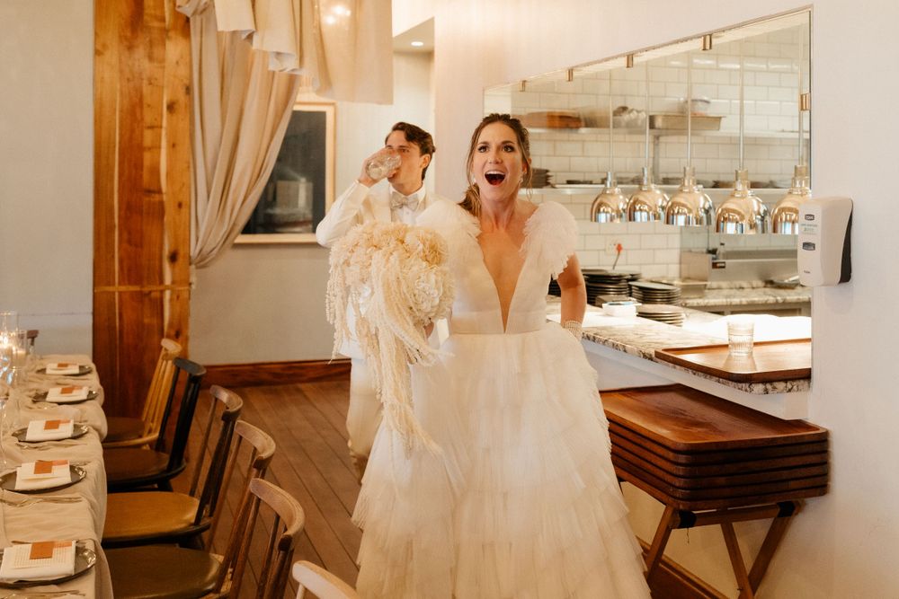 A joyful wedding dress fitting moment captured in warm lighting at a bridal boutique.
