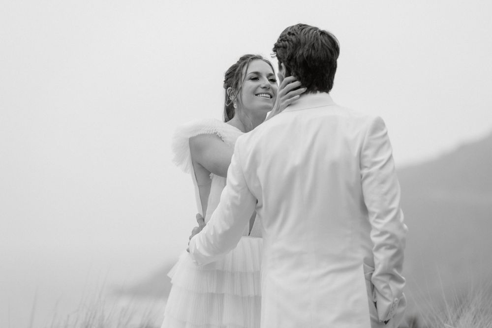 Romantic black and white portrait of a couple embracing in misty mountain scenery.