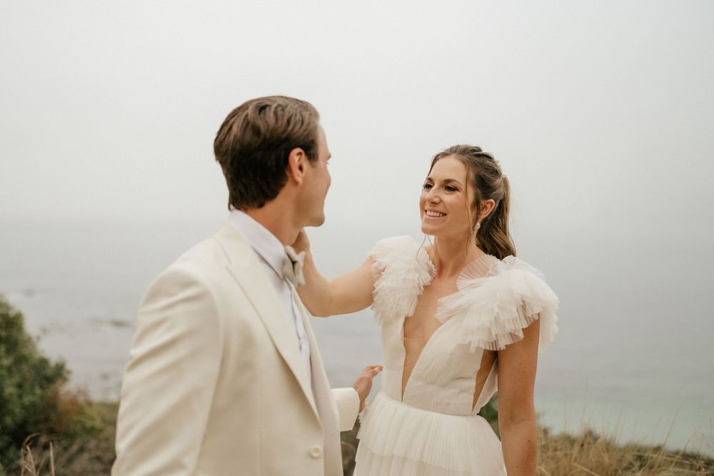 A romantic wedding couple shares an intimate moment on a misty hilltop during their outdoor ceremony.