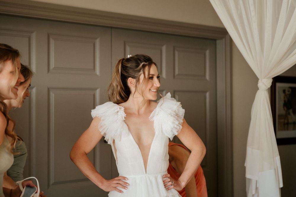 A close-up shot of a wedding dress with delicate ruffled tulle sleeves in an elegant getting ready room.