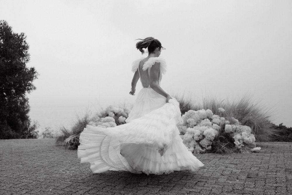 Black and white photo of a billowing wedding dress in motion against a misty background.