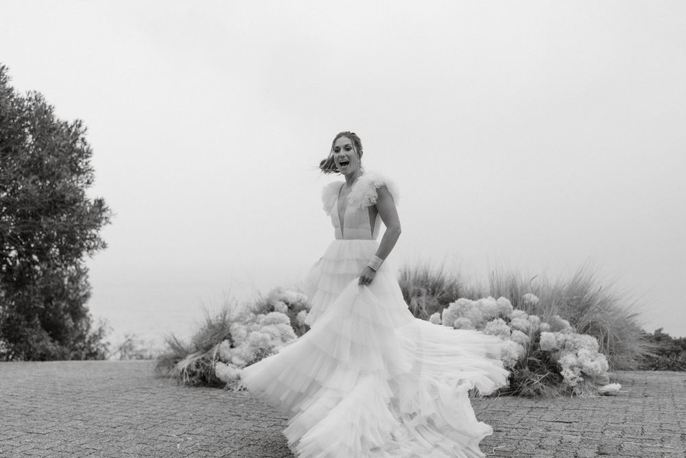 Black and white portrait of bride in flowing gown at scenic overlook.