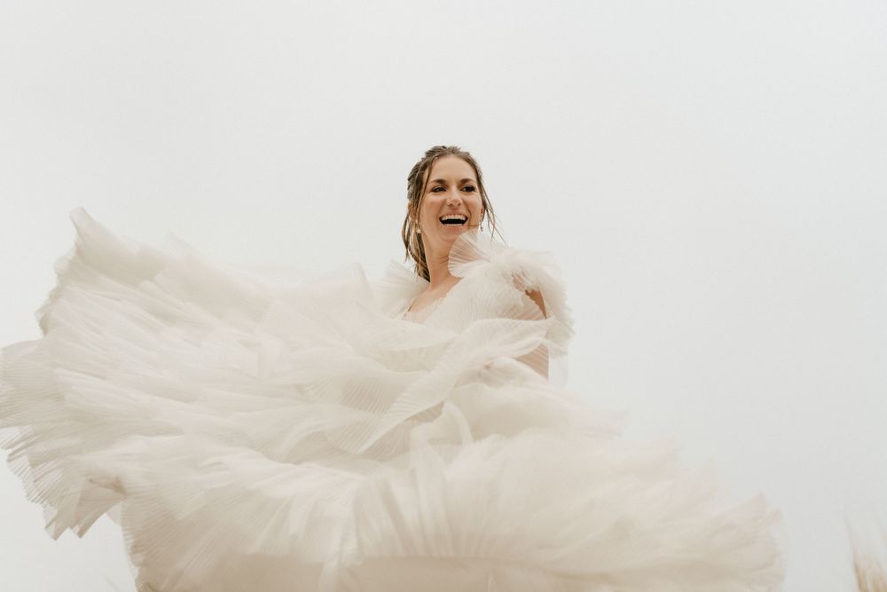 Ethereal bridal portrait with flowing white dress against minimalist backdrop.