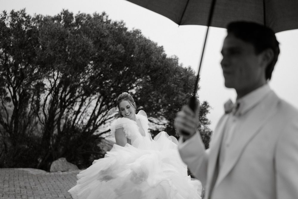 Artistic black and white wedding photo captured under an umbrella with trees in background.