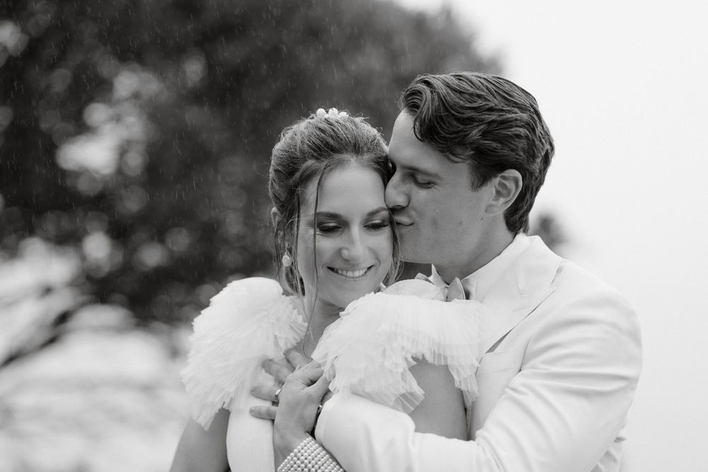 Intimate black and white portrait capturing tender moment between newlyweds outdoors.