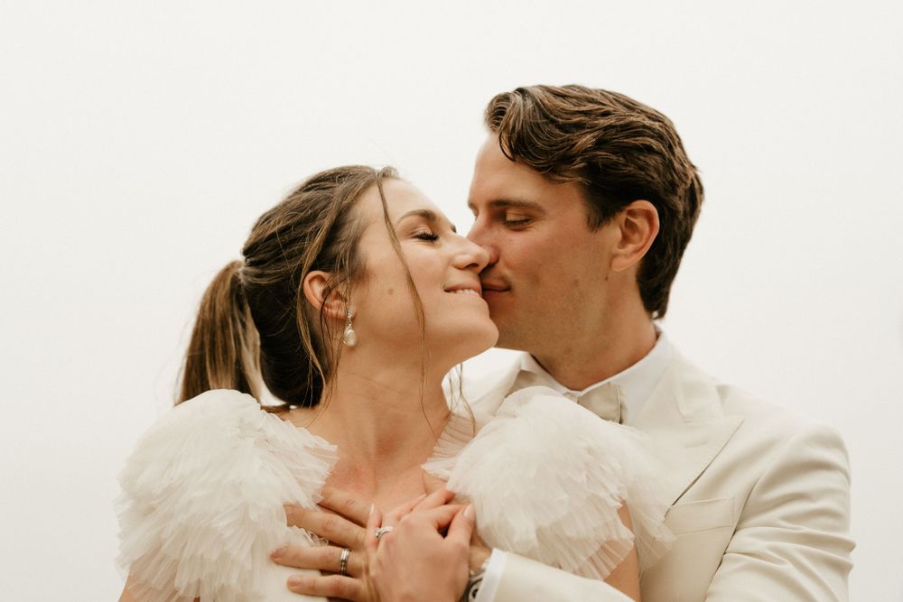 Intimate wedding portrait of couple in cream attire sharing tender moment.