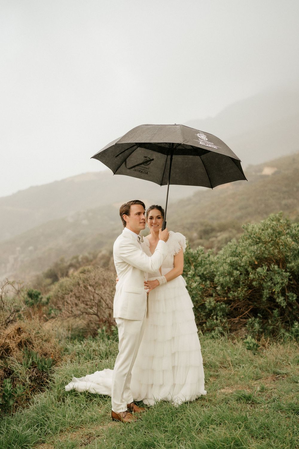 Couple sharing umbrella during romantic mountain wedding photoshoot.