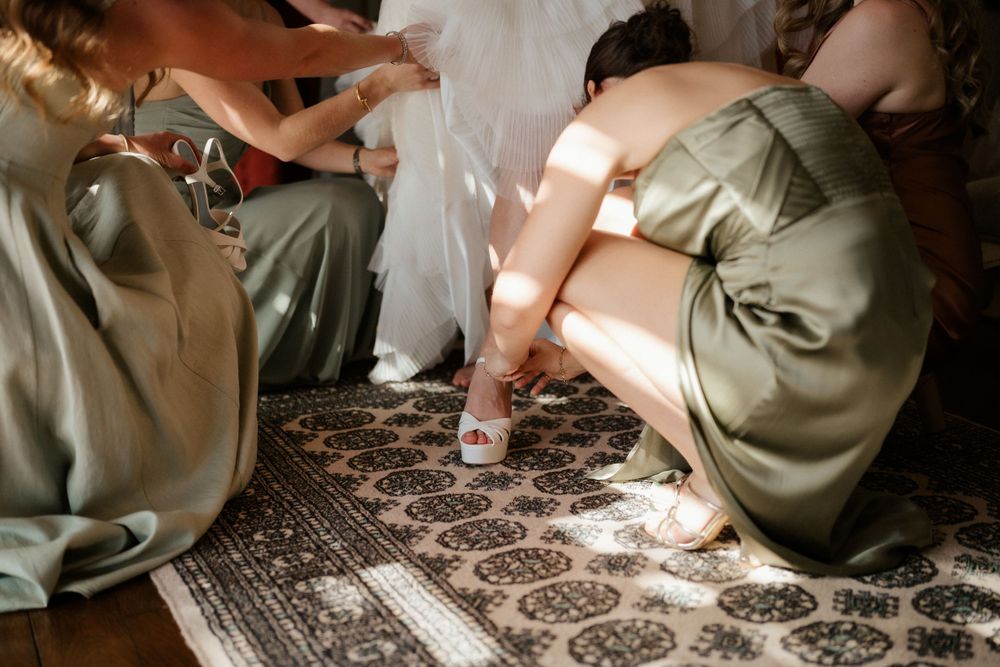 Bridesmaids in sage green dresses helping with wedding preparations.
