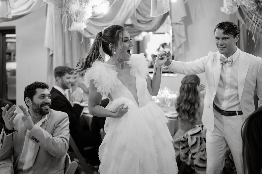 Joyful dancing and celebration captured in black and white at an indoor wedding reception.