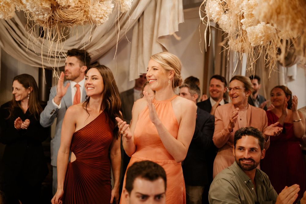 Guests celebrating at an elegant wedding reception with draped fabric and chandeliers.