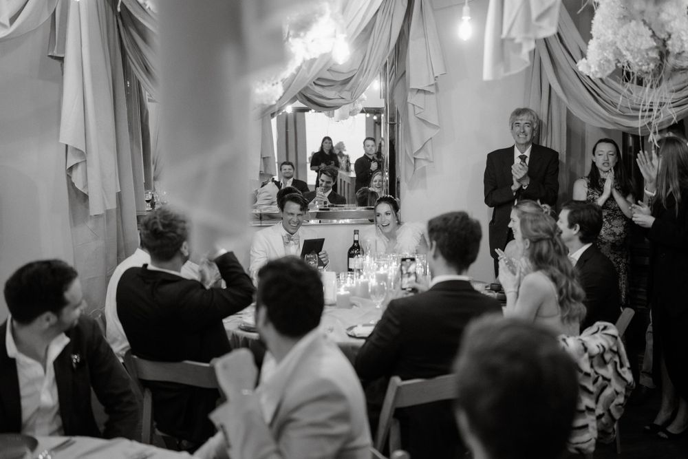 Guests seated at elegant dinner tables with draped fabric decor during an evening wedding reception event.