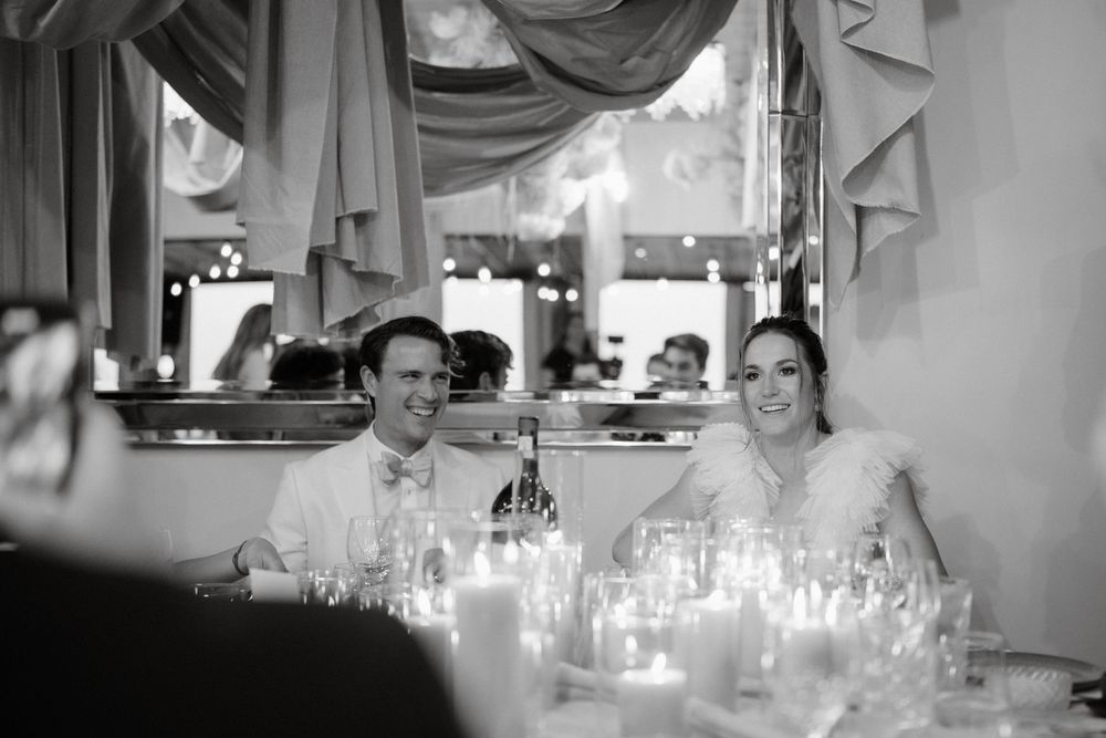 Black and white candid reception photo showing dining tables with candlelight.